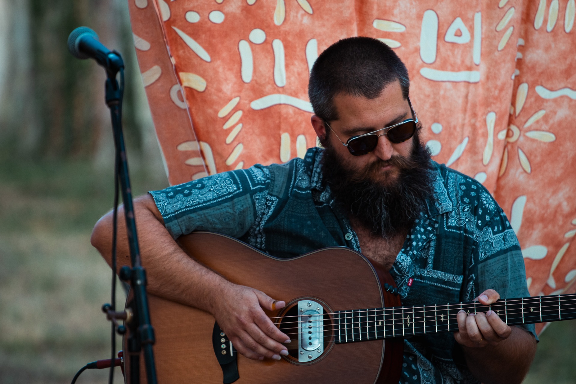 Yoann Wallier en concert, guitare acoustique devant une tenture orangée